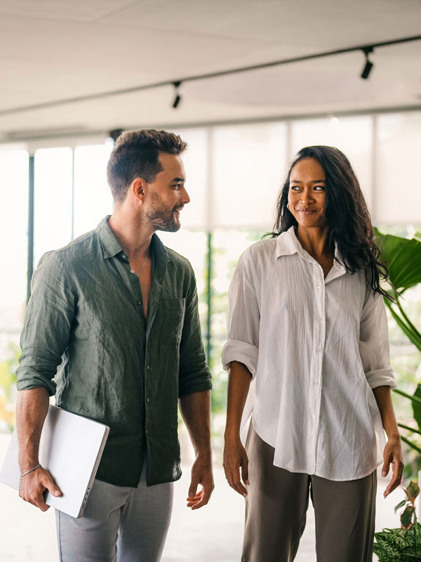 Zwei Personen, die sich in einem hellen, modernen Büro mit großen Fenstern und Grünpflanzen zum Thema Investments in Renewables unterhalten.