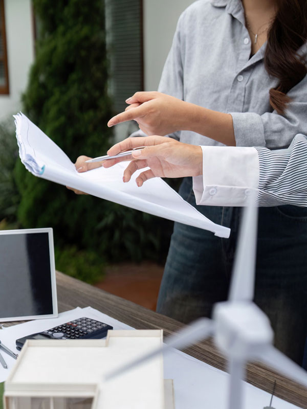 Zwei Personen von SEICON Energy prüfen Dokumente, wobei die eine auf etwas zeigt und die andere einen Stift in der Hand hält.